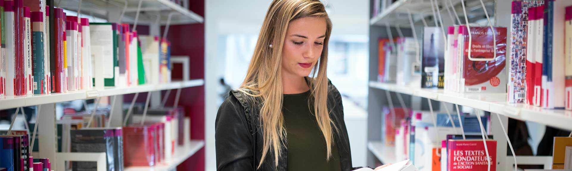 Une étudiante à la bibliothèque lisant un livre