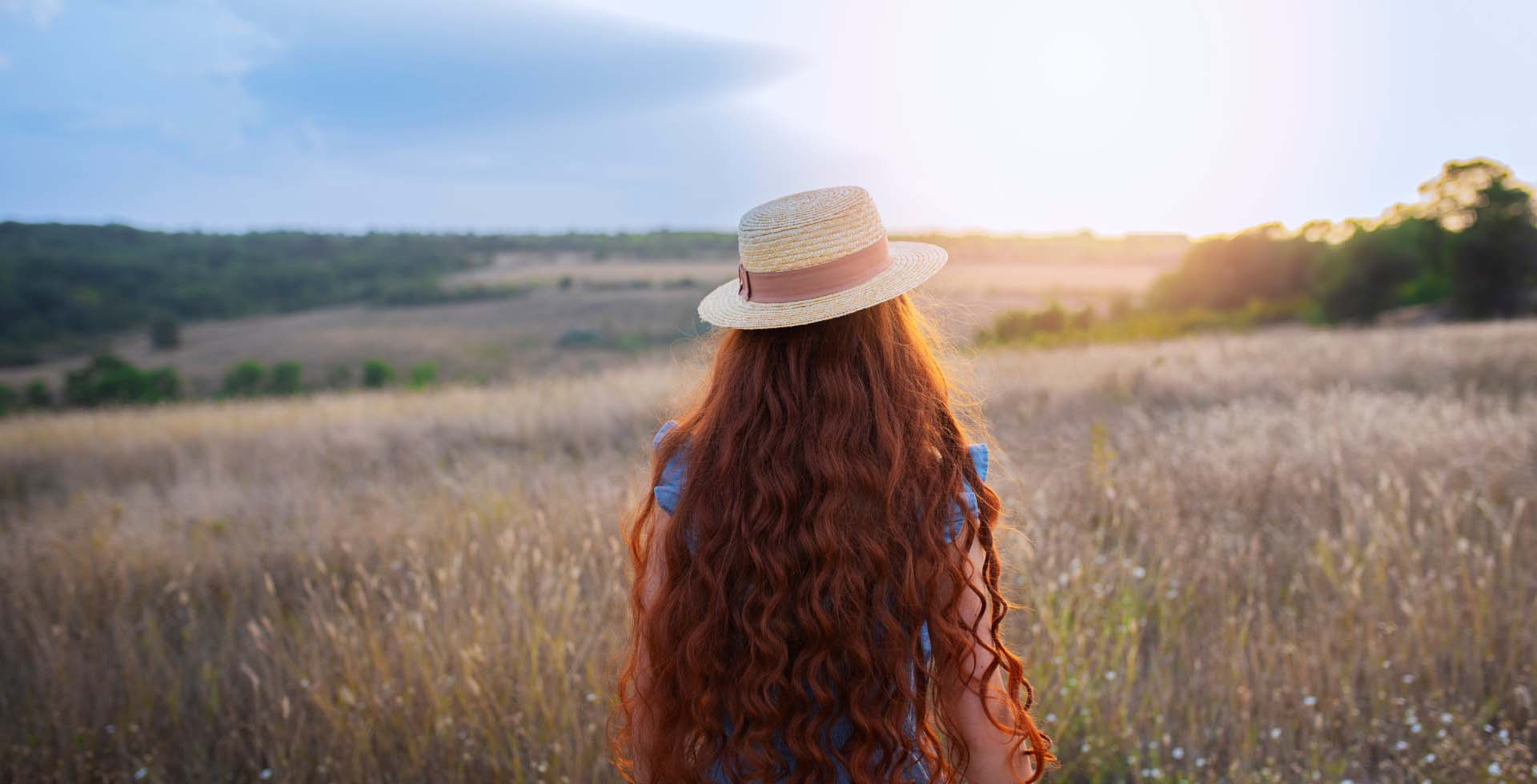 femme de dos avec un chapeau dans un champs